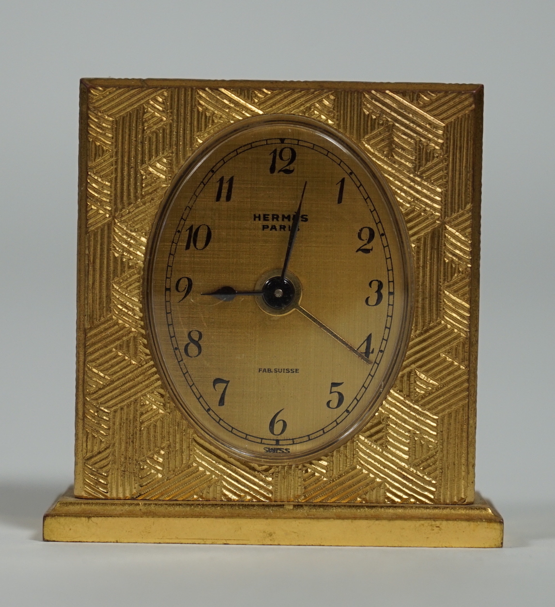 A Hermès travel alarm clock in gilded brass chiselled with H enchassés, height 5cm